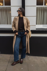 a lady wears a brown trench coat with black top and jeans